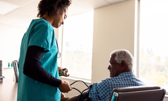 health worker taking blood pressure of seated patient