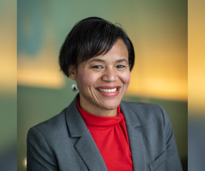 A woman wears a grey suit jacket over her red blouse