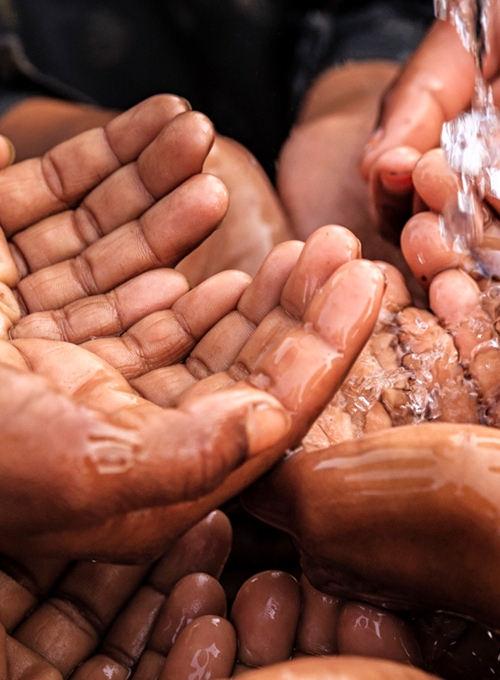 a group of hands under running water