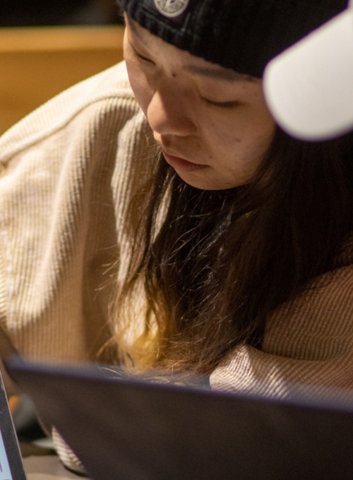 Two students sitting next to each other in a classroom. One student is showing the other a graph on her computer.
