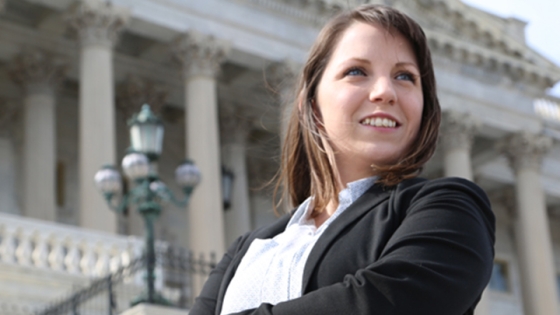 student standing proudly in front of building