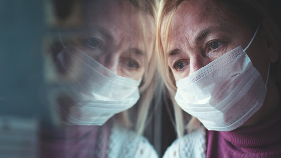 Woman wearing mask staring out window