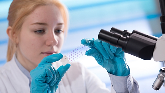 researcher looking at a slide in a lab