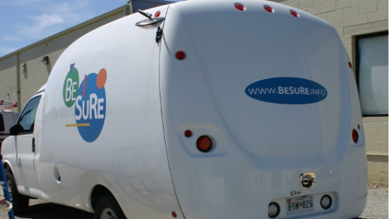 White van with circular BESURE logo parked against the curb