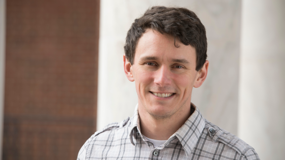 man smiling standing in front of building 
