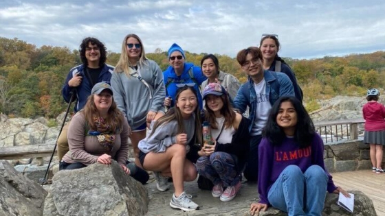 group of students pose on a rock with a natural background