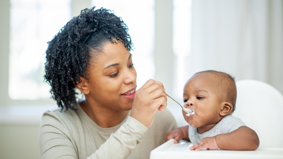 A  baby boy in his highchair as his Mother feeds him