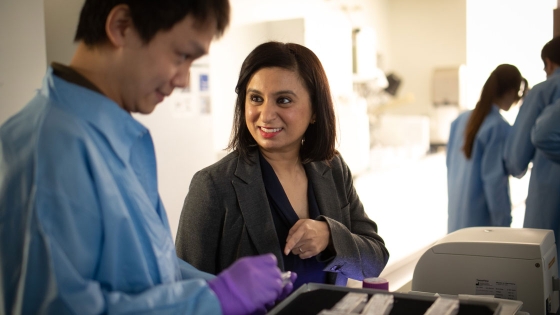 Utthara Nayar in her lab speaking to a student, with others in the background 