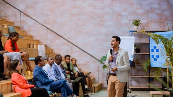 A man with a mic presenting to an audience 
