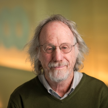 head shot of man in brown sweater and glasses