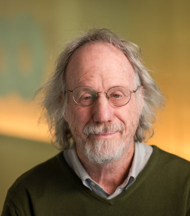 head shot of man in brown sweater and glasses