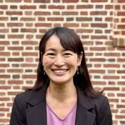 head shot of a female in front of a brick wall