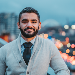 Man in sweater with city lights in background