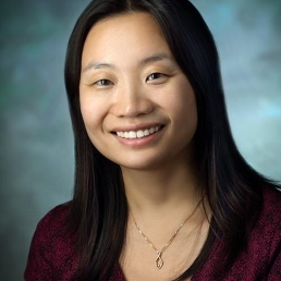 A headshot of Nancy Schoenborn, a woman with a medium-light skin tone and straight black hair that falls just below her shoulders