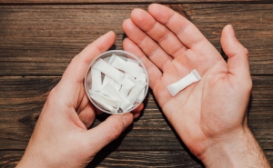 A person holds a container of nicotine pouches