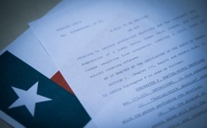 A document with a policy written and the Texas state flag in the background