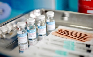 covid vaccine vials, syringes, and bandaids on a metal tray