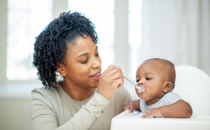 A  baby boy in his highchair as his Mother feeds him