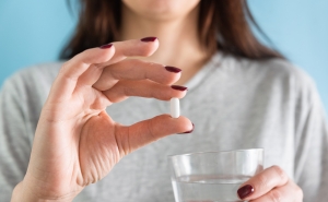 woman holding a pill - face not shown