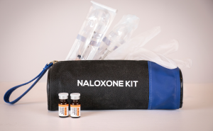 A bag labeled Naloxone Kit with syringes poking out of the top