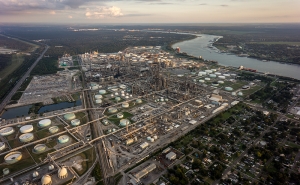 Aerial photo of a large area of petroleum processing plants bordered by residential communities. The Mississippi River snakes along to the east.
