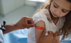 A doctor places a bandaid on the arm of a girl who has just received a vaccine.