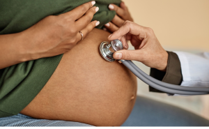 A doctor examines a pregnant belly with a stethoscope