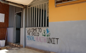 Yellow and gray building with the words &quot;welcome to the mental health unit&quot; painted on them.