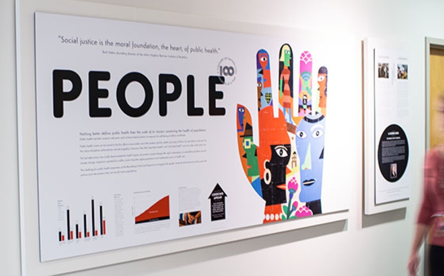 A woman walks by a Centennial art feature focused on People