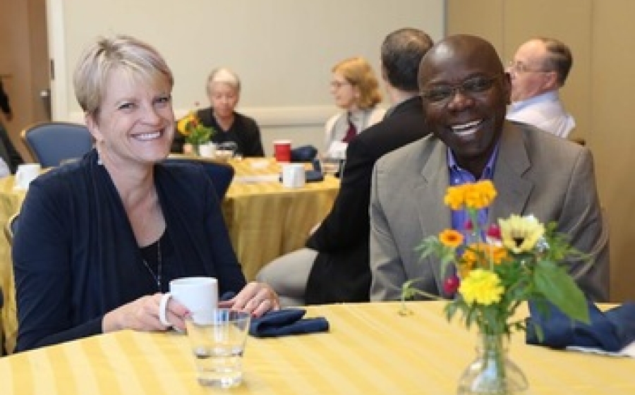 Two people sitting at a table, grinning