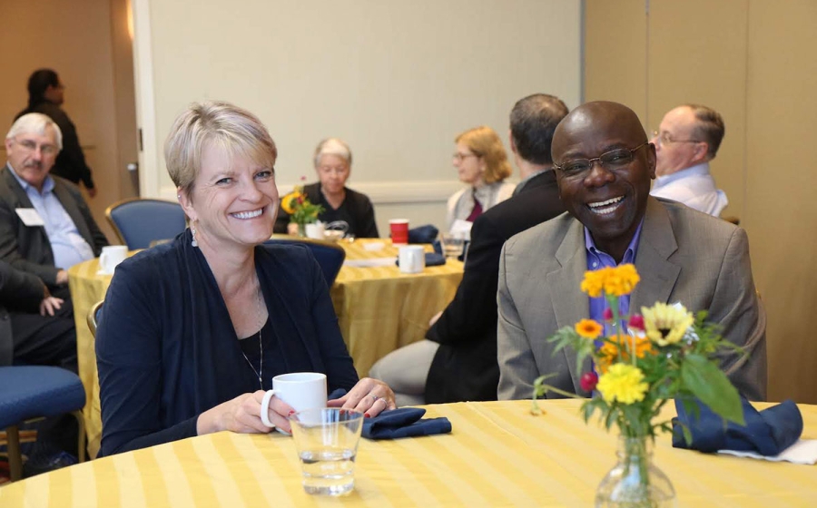 Two people sitting at a table, grinning