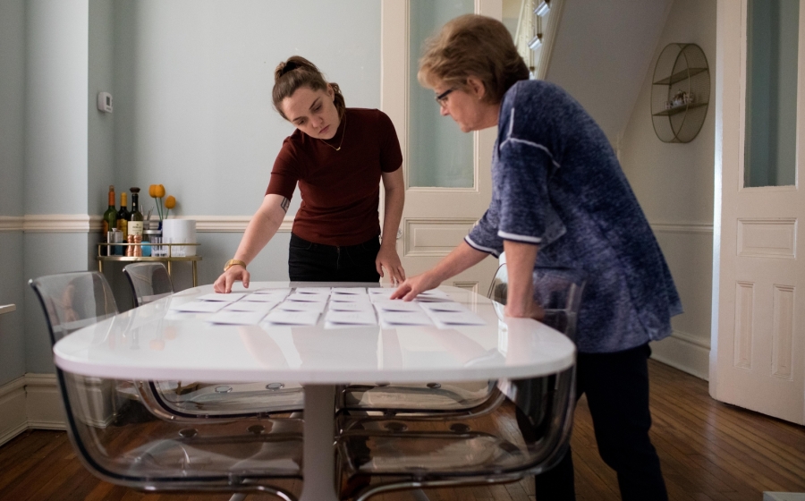 Photo of Amanda Mustard and her mother looking at a series of photographs on a table.