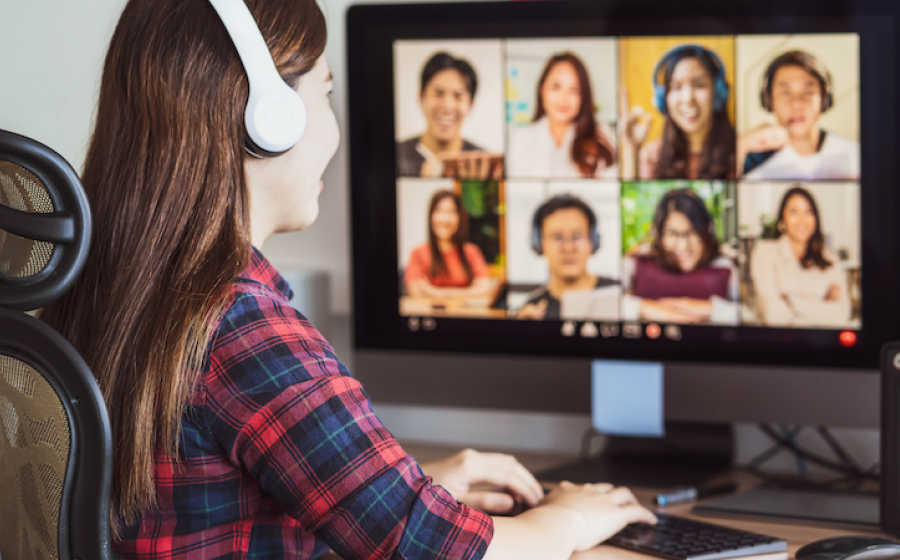Woman wearing headphones in front of a computer monitor with a virtual course class of eight people on screen