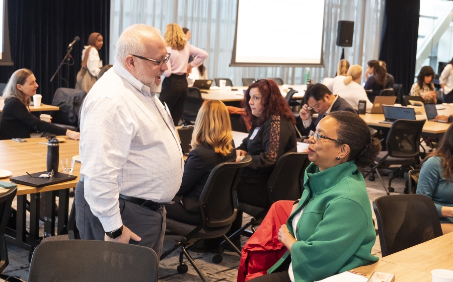 Maryland State Delegate Robbyn T. Lewis is seated at a table smiling with the man who is standing in front of her. Two tables of people are visible behind them.