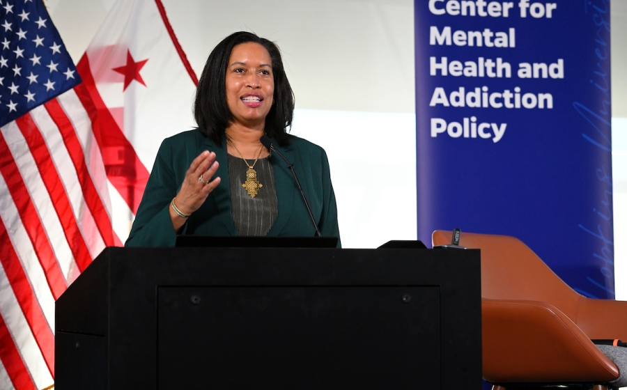 A woman addresses a crowd from behind a podium.