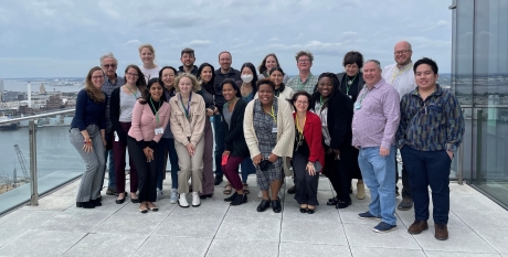 A group of people standing on a balcony with the Baltimore skyline behind them