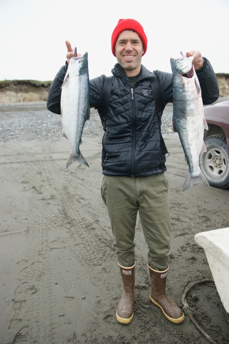 man in red hat holds up two fish