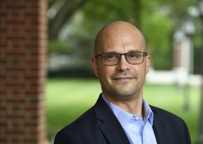man wearing glasses, shirt and suit jacket, standing outdoors 