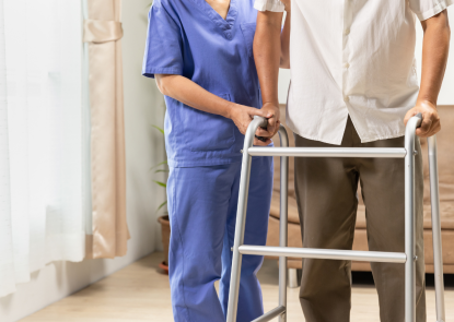 Nurse helping a person walk with a walker