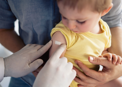 nurse placing bandaid on a child after vaccine
