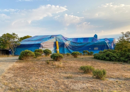 A blue tent covers a structure