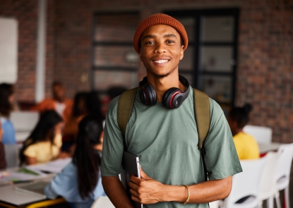 Smiling male student holding laptop