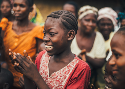 young girl clapping her hands in the center of a crowd of adult women