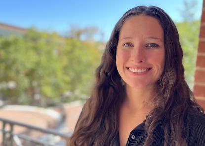 Head shot of young woman with long hair with campus in the background