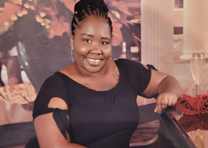A woman wearing a black dress smiles at the camera.