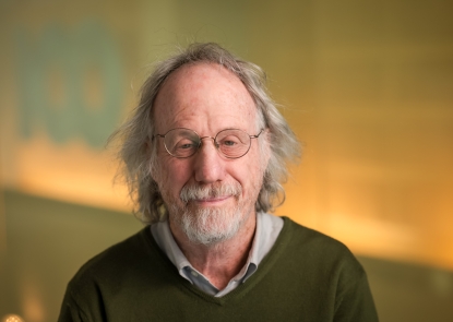 head shot of man in brown sweater and glasses